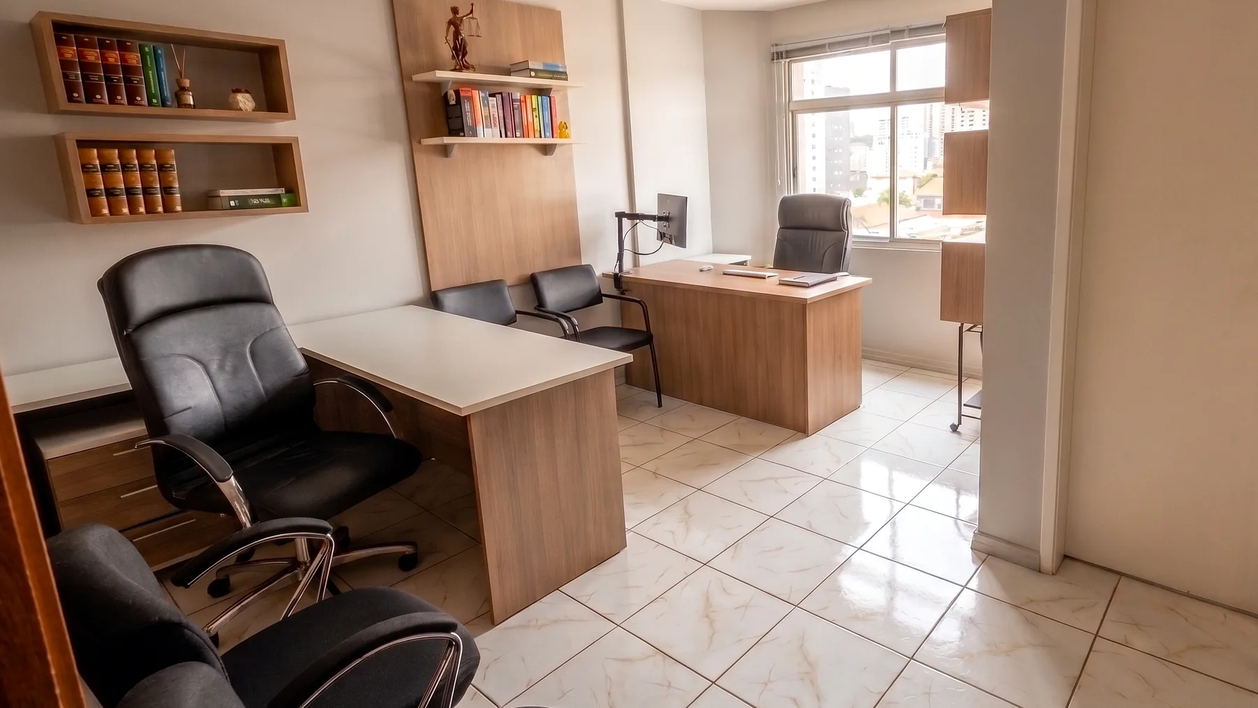 Sala de atendimento do escritório, com mesa de trabalho, cadeiras para visitantes e janela com vista para São Leopoldo